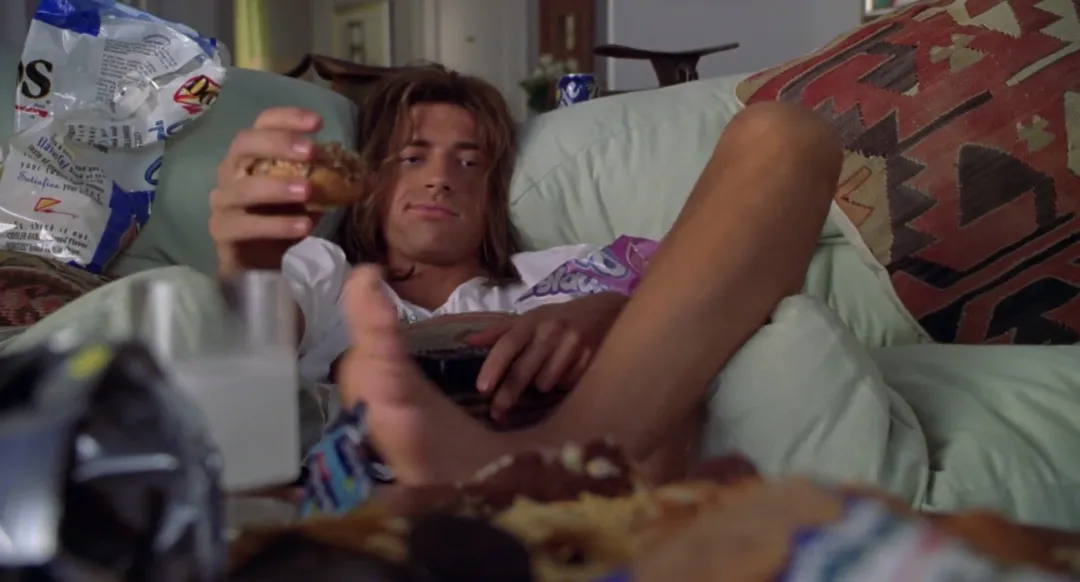 Brendan Fraser lounging, surrounded by snacks.