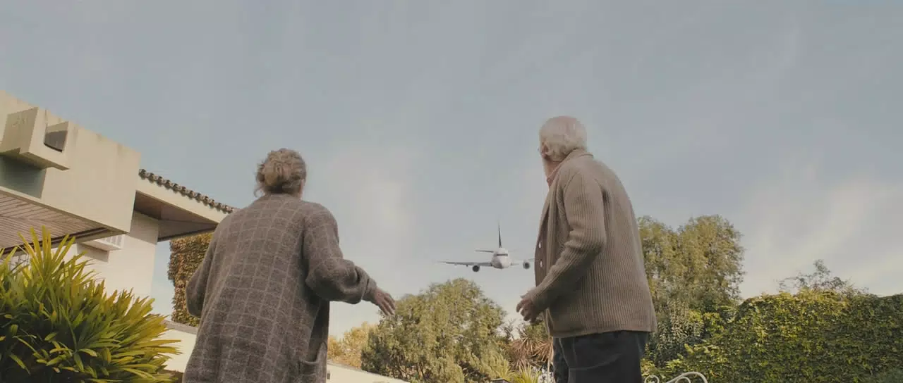 An older couple watch as a plane comes for them.