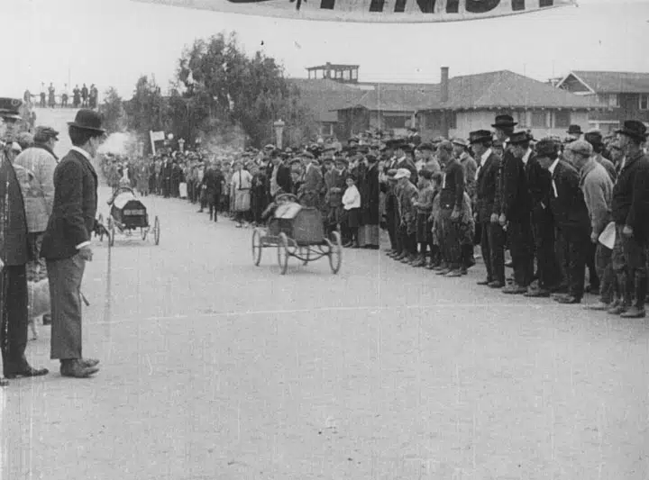 Charlie Chaplin looking at an old motorless racecar