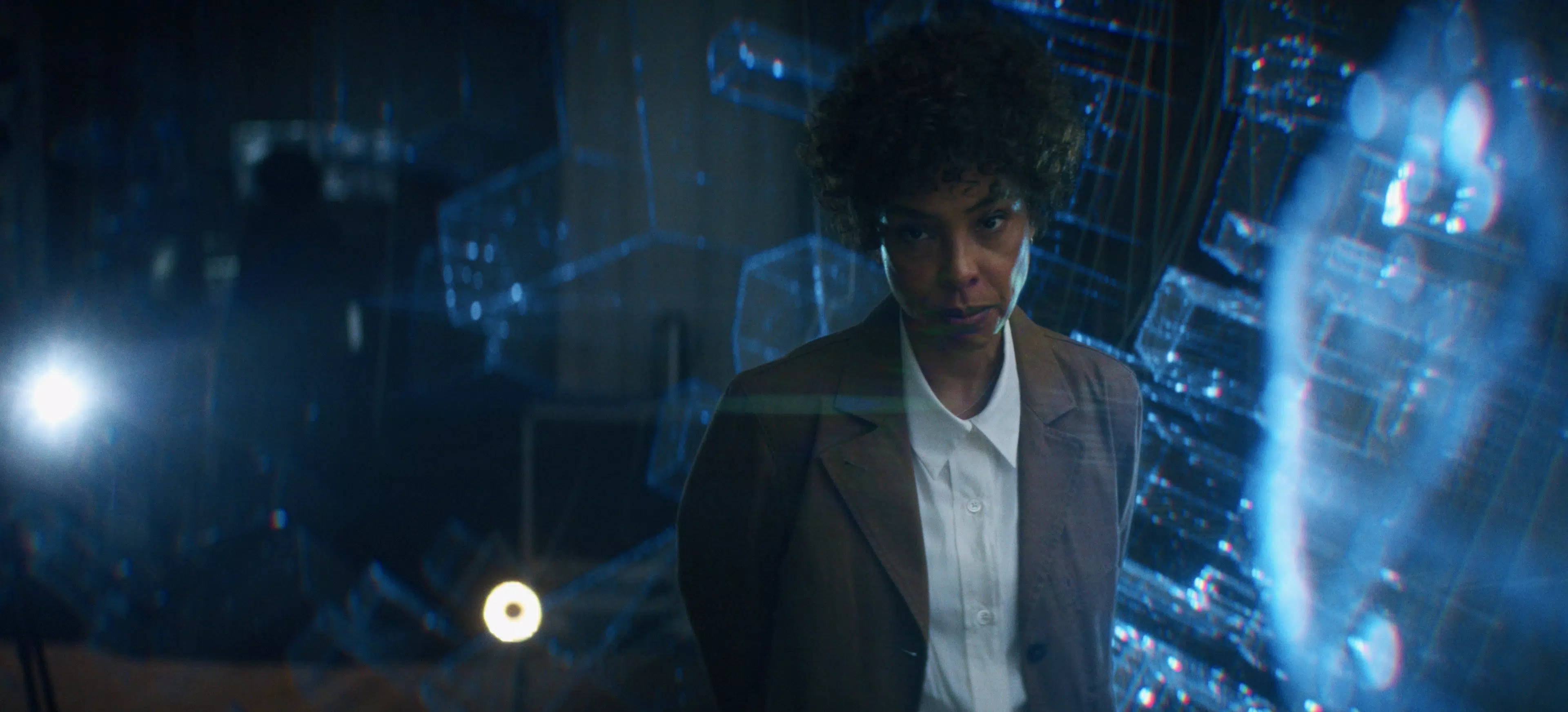Sophie Okonedo posing between blue projections which represent a supercomputer.