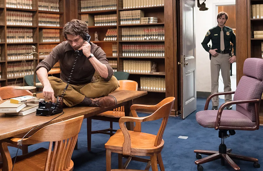 Zac Efron sitting on a table dialling a phone