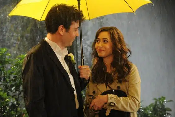 This may contain: a man and woman standing under an umbrella in the rain, one holding a flower