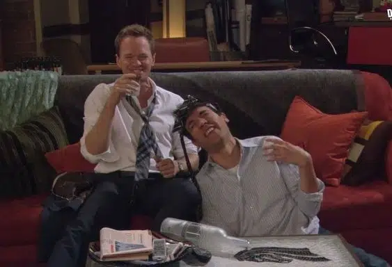 This may contain: two men sitting on a couch one is holding a microphone and the other has his mouth open