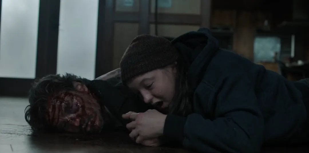 A young girl lies next to an older man's bloody body