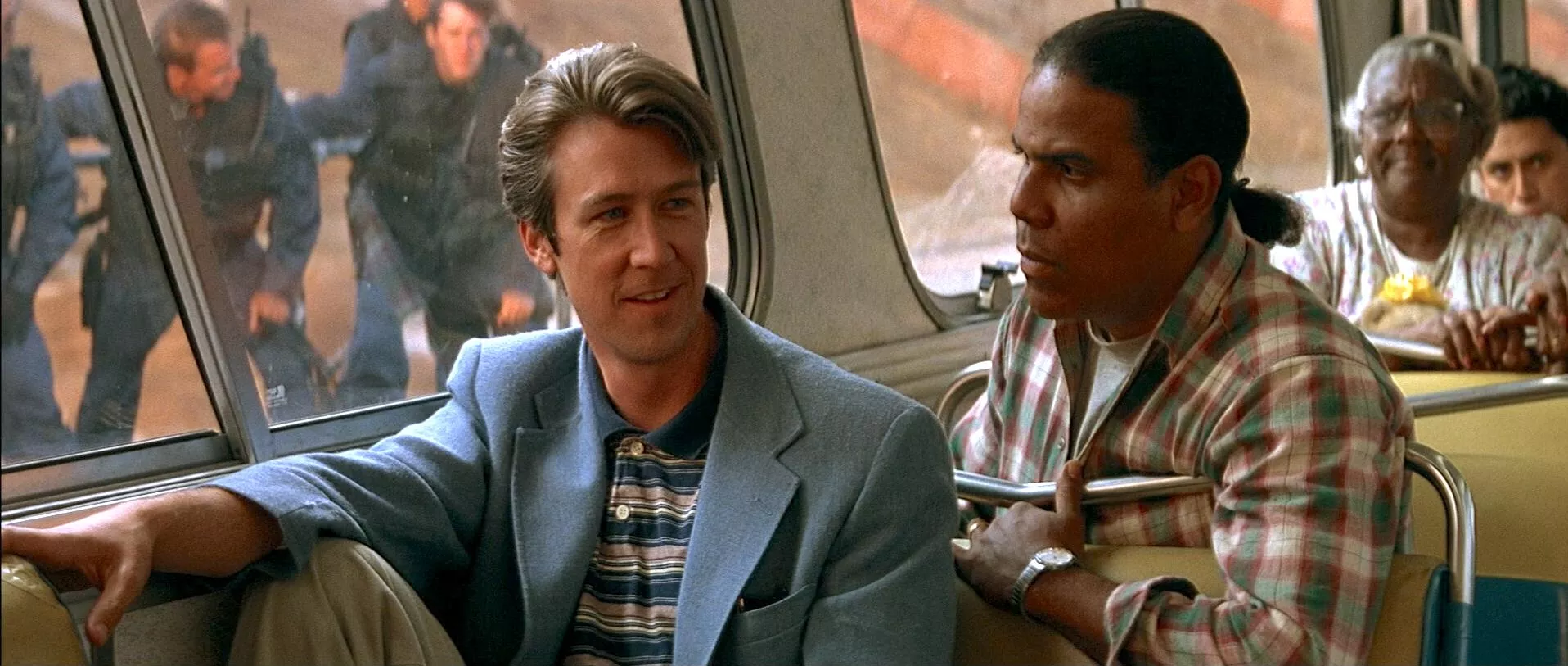 2 men sit next to each other on a bus
