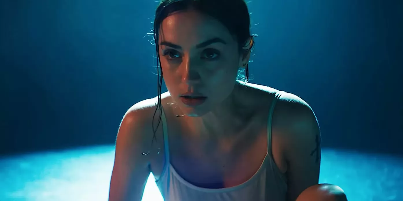 a ballerina crouches onstage, resting in a spotlight