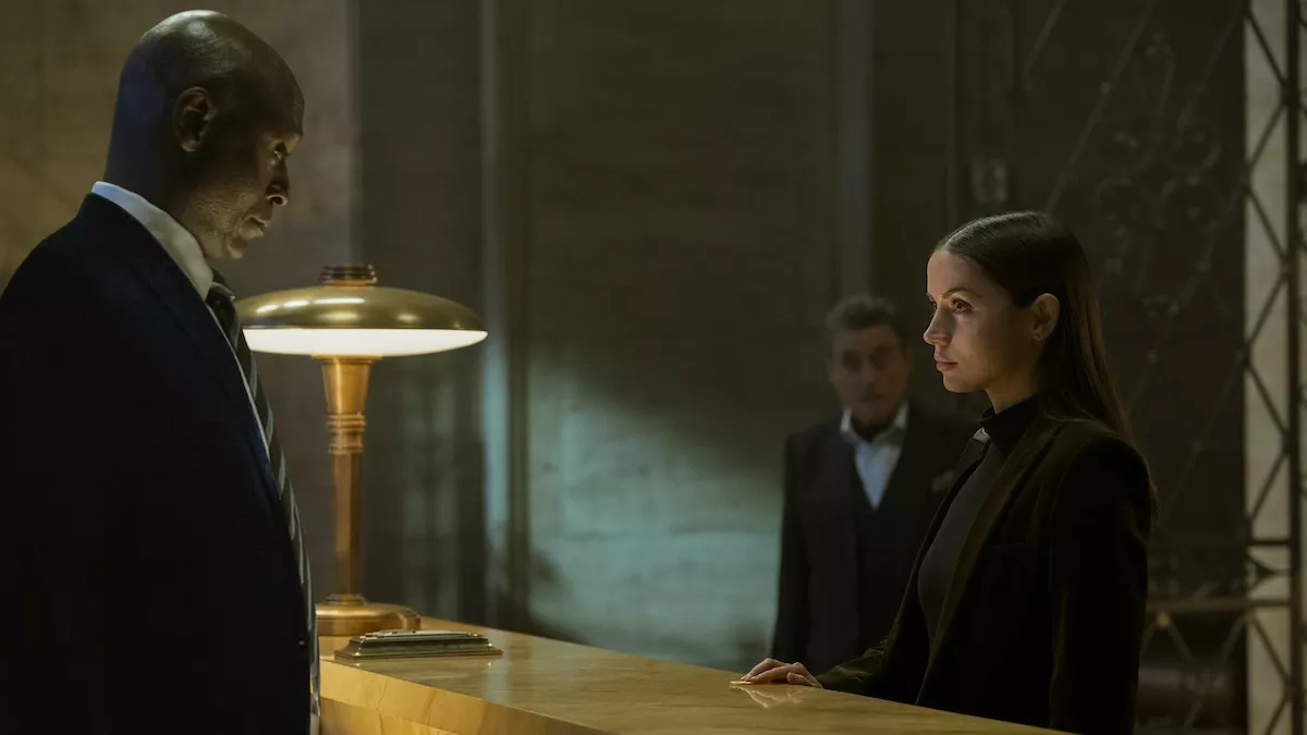 A man and woman stand on opposite sides of a counter in a hotel lobby